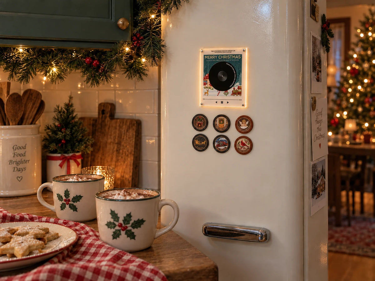 The Gifty Woodland Christmas Record Light glowing on a fridge beside hot chocolate, Christmas lights and a decorated tree